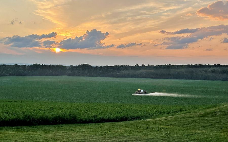 Photo of Alliance Agri-Turf's agricultural equipment driving through field with sunset in the background About Alliance Agri-Turf